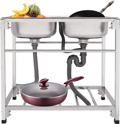 A commercial stainless steel double sink with various kitchen items and fruits on top.