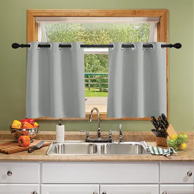 A kitchen sink area with curtains over the window, a cutting board with vegetables, and a knife block.
