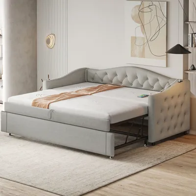 A light gray upholstered daybed with a pull-out trundle bed is shown in a modern living room setting.