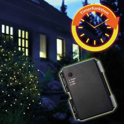 A house at night with Christmas lights on a tree and a control box in the foreground.