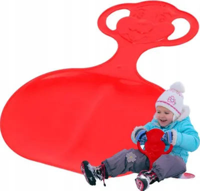 A child is sitting on a red sled in the snow.