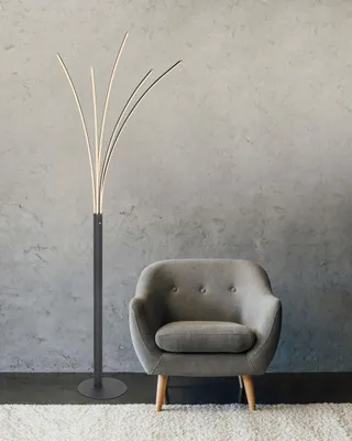 A modern floor lamp and armchair in a room with a concrete wall.