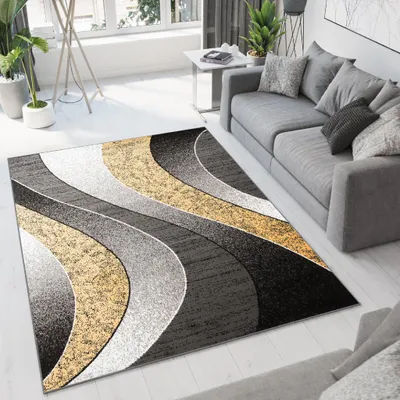 A modern living room with a grey sofa and a rug with a wavy pattern in grey, black, and gold.