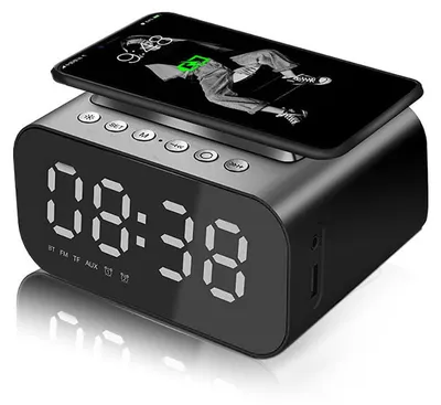 A black digital alarm clock with a smartphone placed on top, charging wirelessly.