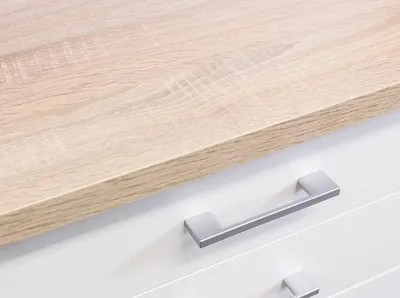 Close-up view of a white cabinet with two silver drawer pulls, topped with a light wood surface.