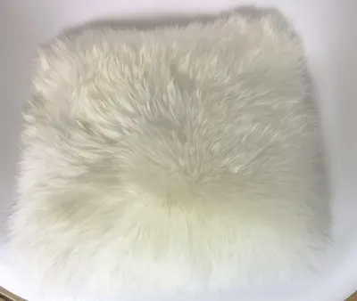 A white sheepskin seat cushion on a white background.