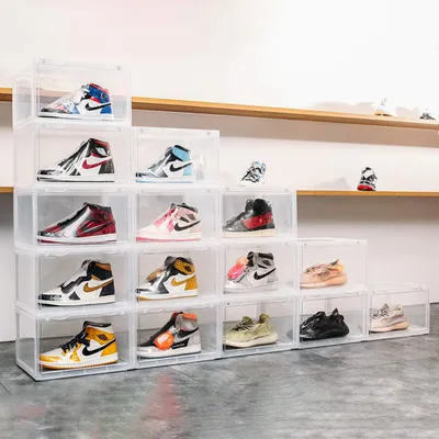 A collection of clear plastic shoe boxes stacked in a pyramid formation, each containing a pair of sneakers.