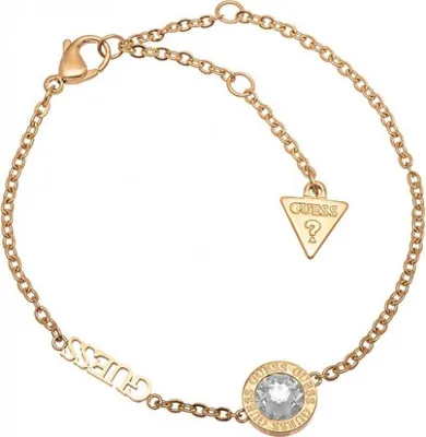 A close-up studio shot of a gold-colored Guess bracelet with a clear gemstone.
