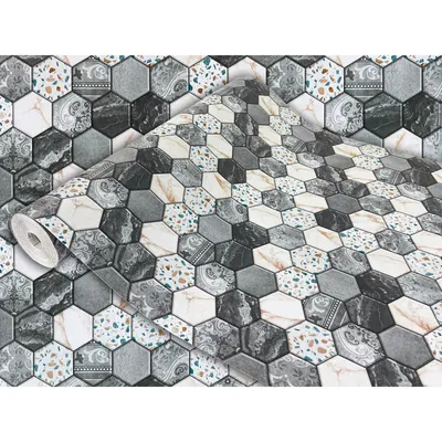 A roll of hexagonal tile patterned wallpaper is shown partially unrolled, with the pattern continuing on the flat surface behind it.