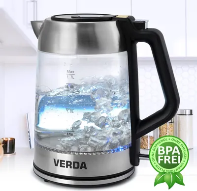 A glass and stainless steel electric kettle filled with water and ice, placed on a countertop with a blurred kitchen background.