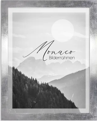 A framed black and white photograph of a mountain landscape with a large sun in the sky.