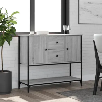 A gray sideboard with black accents is placed in a room with a large window and white brick walls.