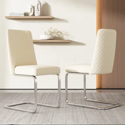 Two beige dining chairs with silver metal legs are placed on a light gray rug in front of a wall with two wooden shelves.