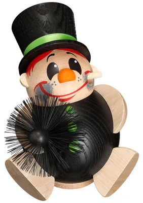 Ein fröhlicher Schornsteinfeger aus Holz mit rotem Haar und einem schwarzen Zylinderhut hält einen Kehrbesen in der Hand und trägt ein schwarzes Outfit mit grünen Knöpfen während er lächelnd in die Ferne blickt