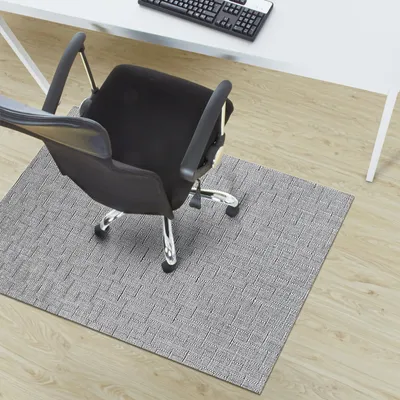 An office chair on a gray chair mat in front of a white desk.