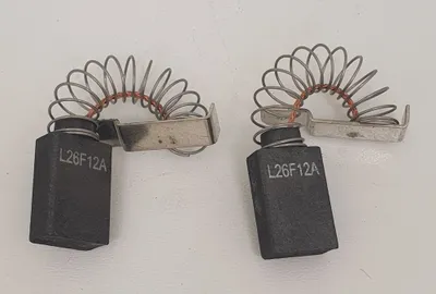 Two carbon brushes with springs are shown on a white background.