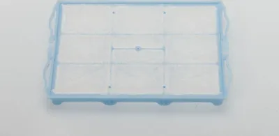 A close-up, slightly angled view of a white filter with a light blue plastic frame, set against a light gray background.