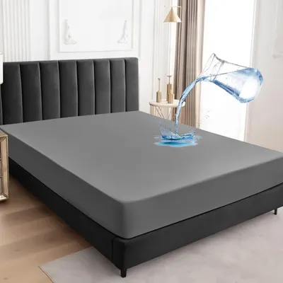 A gray mattress protector on a bed, with water being poured onto it to demonstrate its waterproof feature.