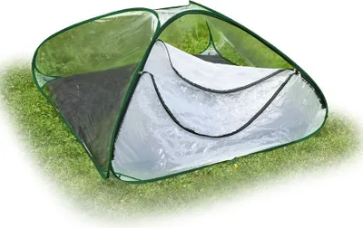 A pop-up greenhouse tent on grass.