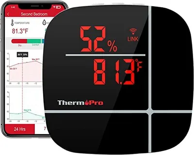A digital thermometer and hygrometer device next to a smartphone displaying its interface.