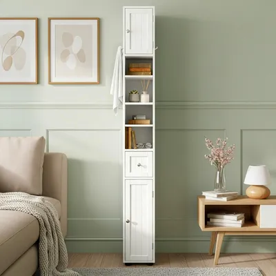 A tall, narrow white cabinet with shelves and a drawer stands next to a sofa and a side table in a room with green walls.