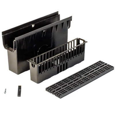 A black drainage system kit is laid out on a white background. The kit includes a channel, a basket, and a grate.