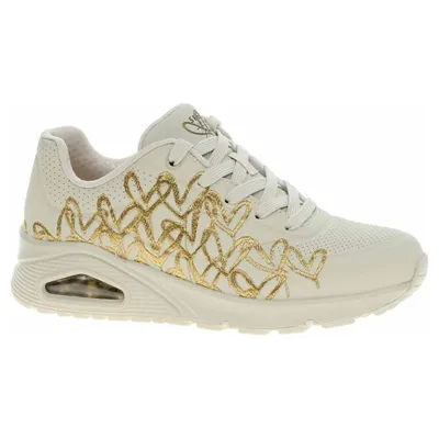 A side view of a single beige Skechers sneaker with gold heart detailing.