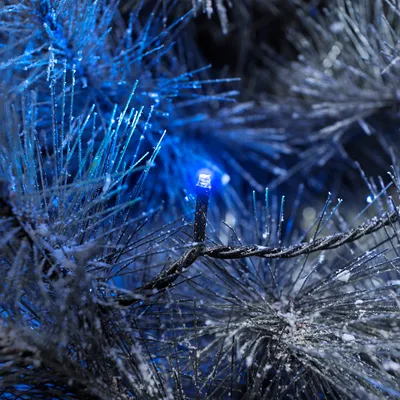 A close-up view of a string of blue LED lights on a frosted artificial Christmas tree.