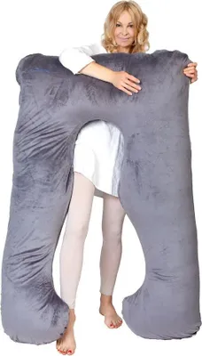 A woman is holding a large U-shaped pillow.
