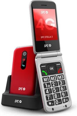 A red flip phone and its charging dock are shown against a white background. The phone is open, revealing the keypad and screen.