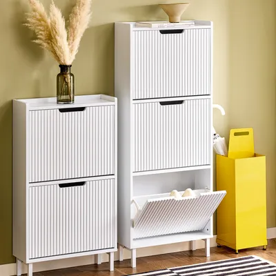 Two white shoe cabinets and a yellow umbrella stand are shown in a room with a light green wall and a striped rug.