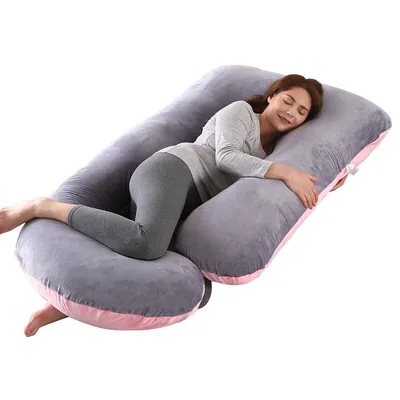 A woman is lying on a U-shaped pregnancy pillow.
