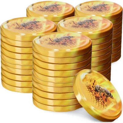 Stacks of golden lids with a bee and flower design, with one lid in the foreground.