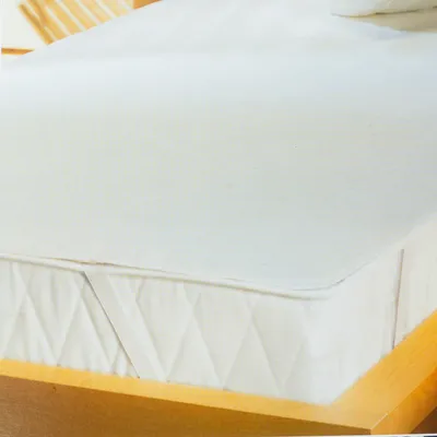 A close-up of a white mattress topper on a wooden bed frame.