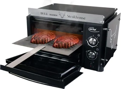 A high-temperature grill with two steaks cooking inside.
