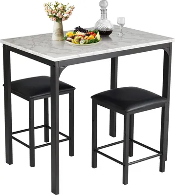 A white marble-patterned bar table with two black bar stools, a vase of flowers, a decanter, and a fruit bowl on the table.