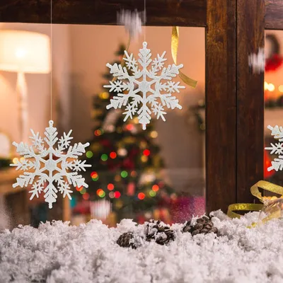 Christmas decorations with snowflakes hanging in front of a Christmas tree.