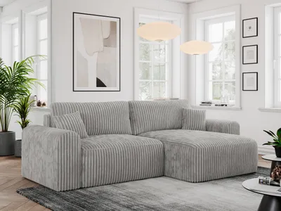 A modern living room with a gray cord sofa, plants, and artwork.