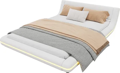 A white bed with pillows and blankets, illuminated by LED lights.
