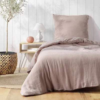 A bedroom scene with a bed, nightstand, and plant.