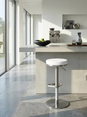 Zwei weiße Barhocker mit markanter dreieckiger Fußablage ergänzen die offene High-End-Küche neben einer freistehenden Kochinsel._#sku_SAFWL1.294#