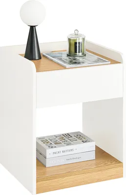 A white and wood-tone nightstand with a lamp and a candle on top, and books on the shelf below.