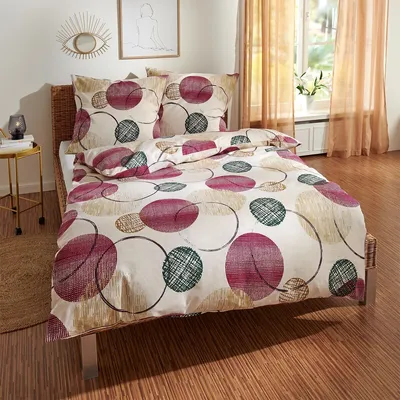 A bed with bedding featuring a circular pattern, set in a bedroom with curtains and a window.