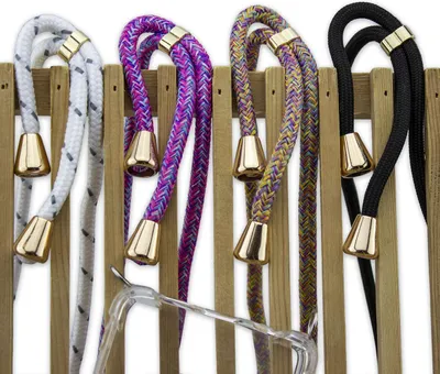 Four braided lanyards with gold-colored metal tips are displayed hanging from a wooden rack. A clear plastic phone case is visible in the foreground.