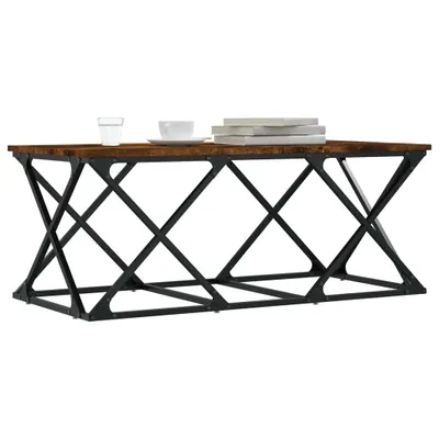 A coffee table with a wooden top and black metal base, decorated with a glass of water, a cup and saucer, and a stack of books.