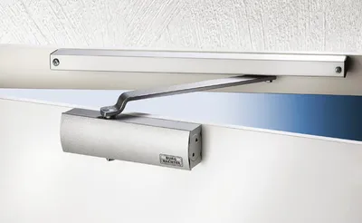 A close-up shot of a door closer mounted on a door and door frame.