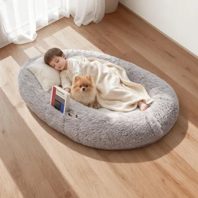 A child and a dog are sleeping on a large, plush dog bed.
