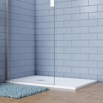 A modern shower tray with blue tiled walls and a blue rug on a wooden floor.