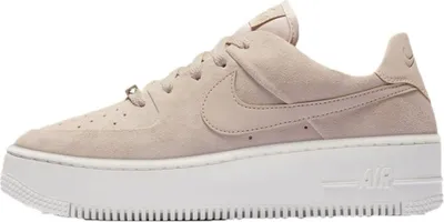 A side view of a single Nike Air Force 1 Sage Low sneaker in a particle beige colorway with a white platform sole, isolated on a white background.