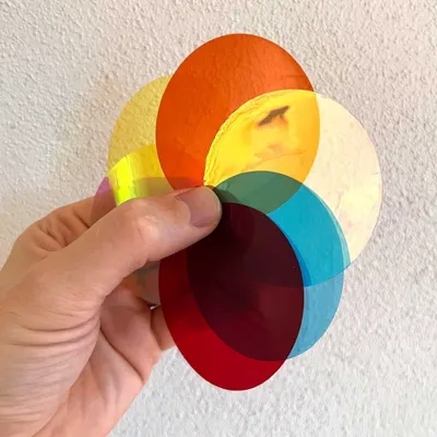 A hand holding several colored circular filters.